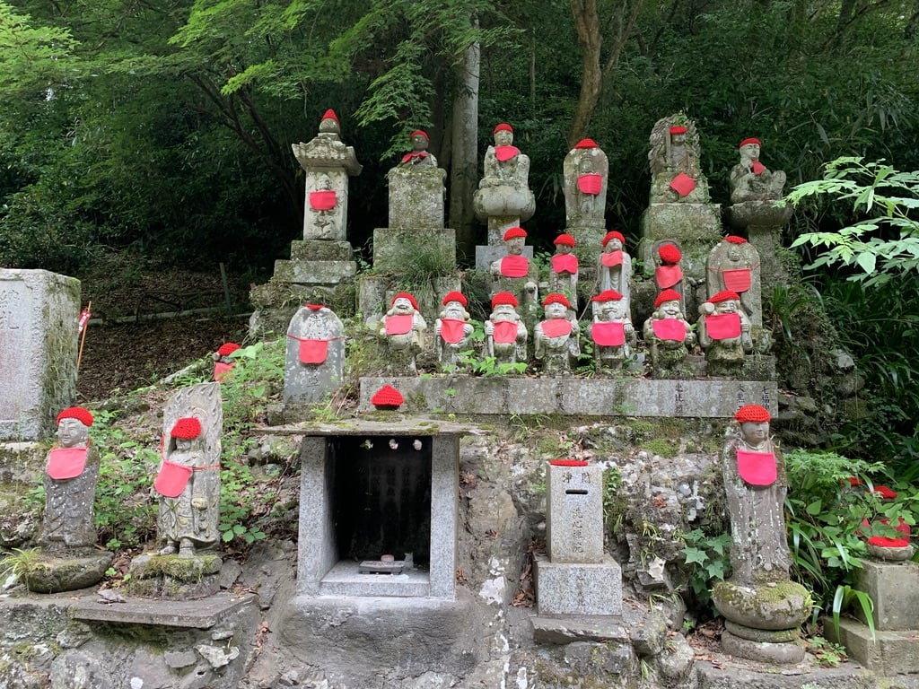 statues in the forest with a red beanny.