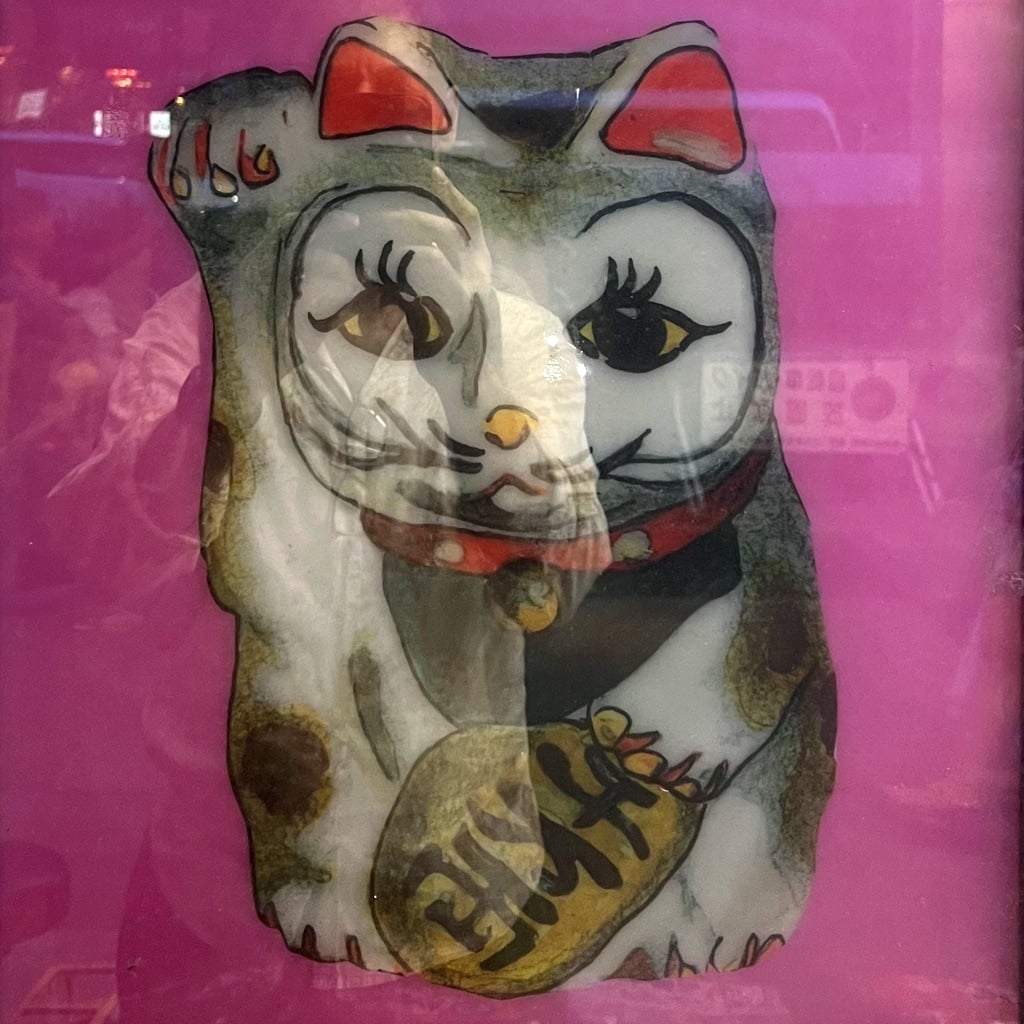 Pawn of lucky cat (manekineko) in the air with my reflection in the window